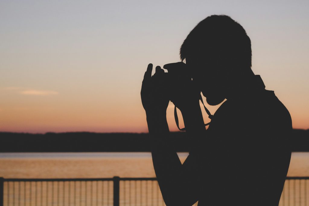 Silhouette of a photographer taking a picture at sunset over the water